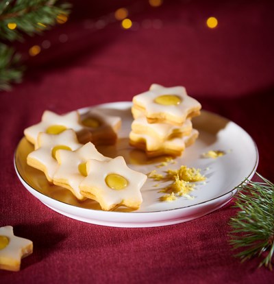 Kekse in Sternform mit einer cremigen Zitronenfüllung auf einem weißen Teller.
